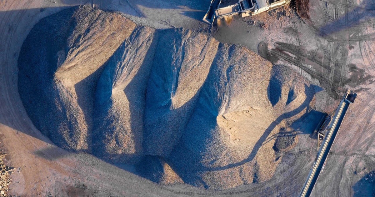 An aerial view of a large aggregate stockpile beside a conveyor.
