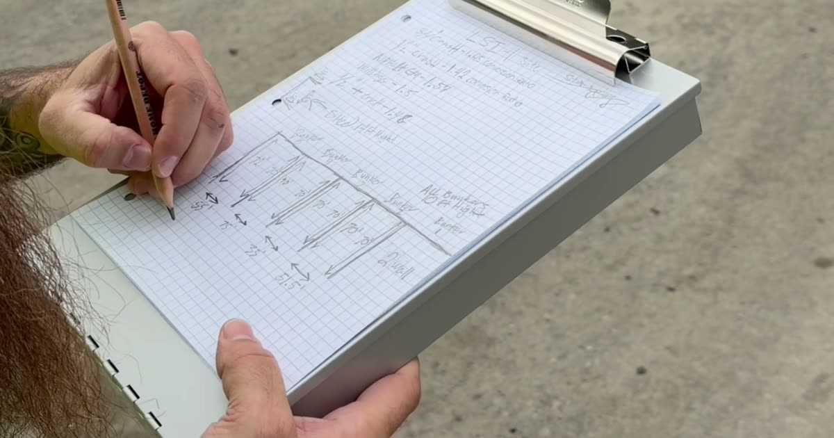 A hand sketches a yard of numbered stockpile bunkers on graph paper on a clipboard.